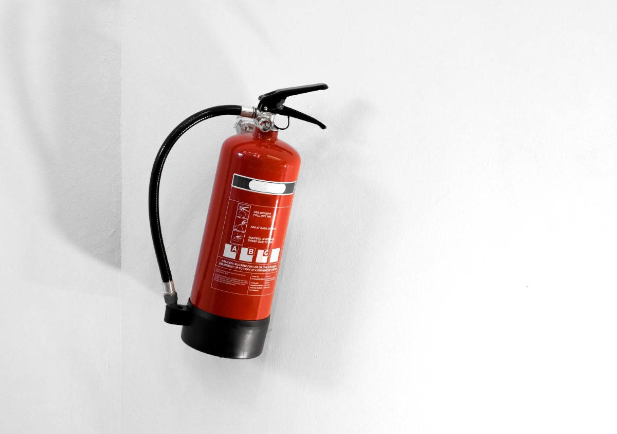 Red fire extinguisher mounted on a white wall